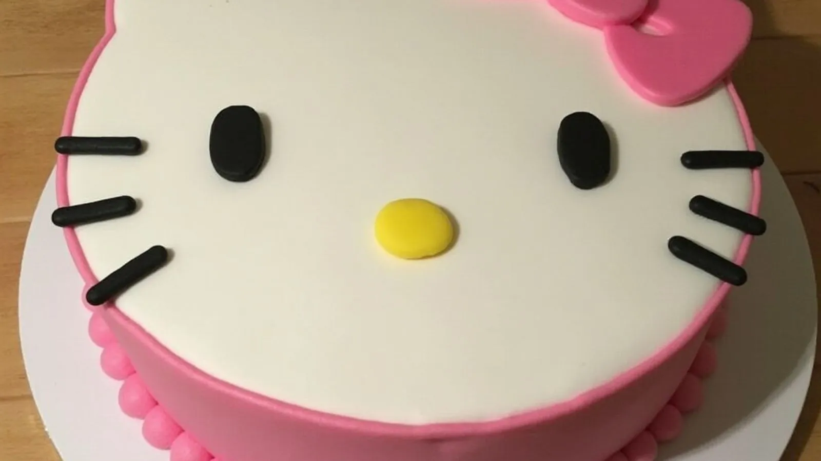 A beautifully decorated Hello Kitty cake with pink frosting, cute face, and bow on top.